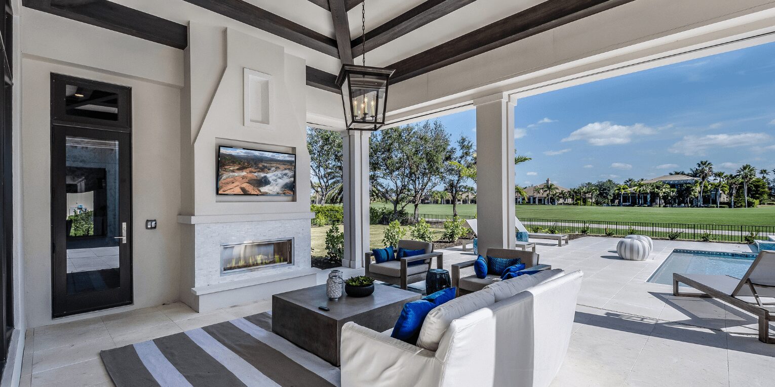 Outside living area with couch, fireplace, TV underneath a lamp chandelier