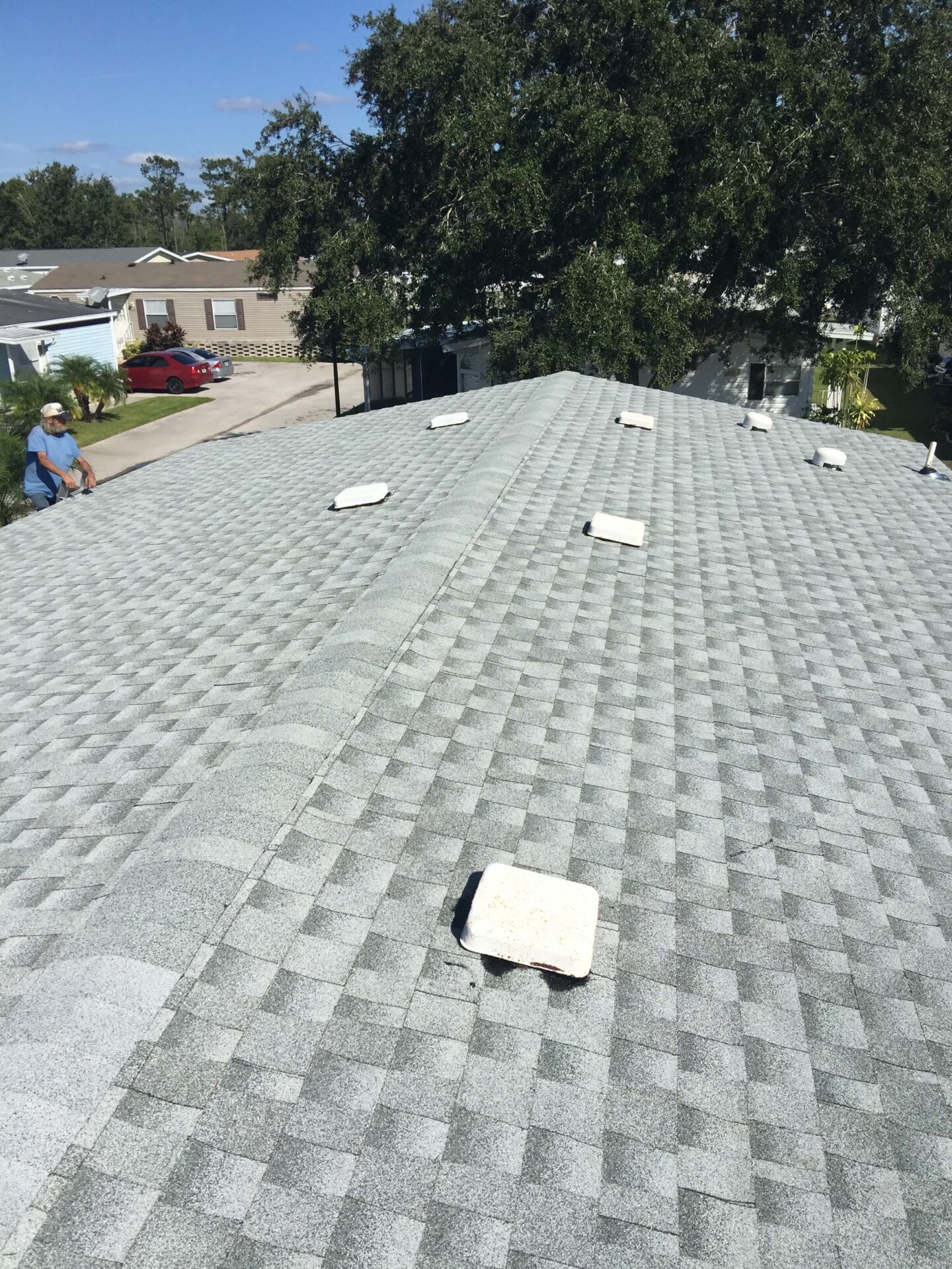 Roofer on a ladder overlooking a finished roof